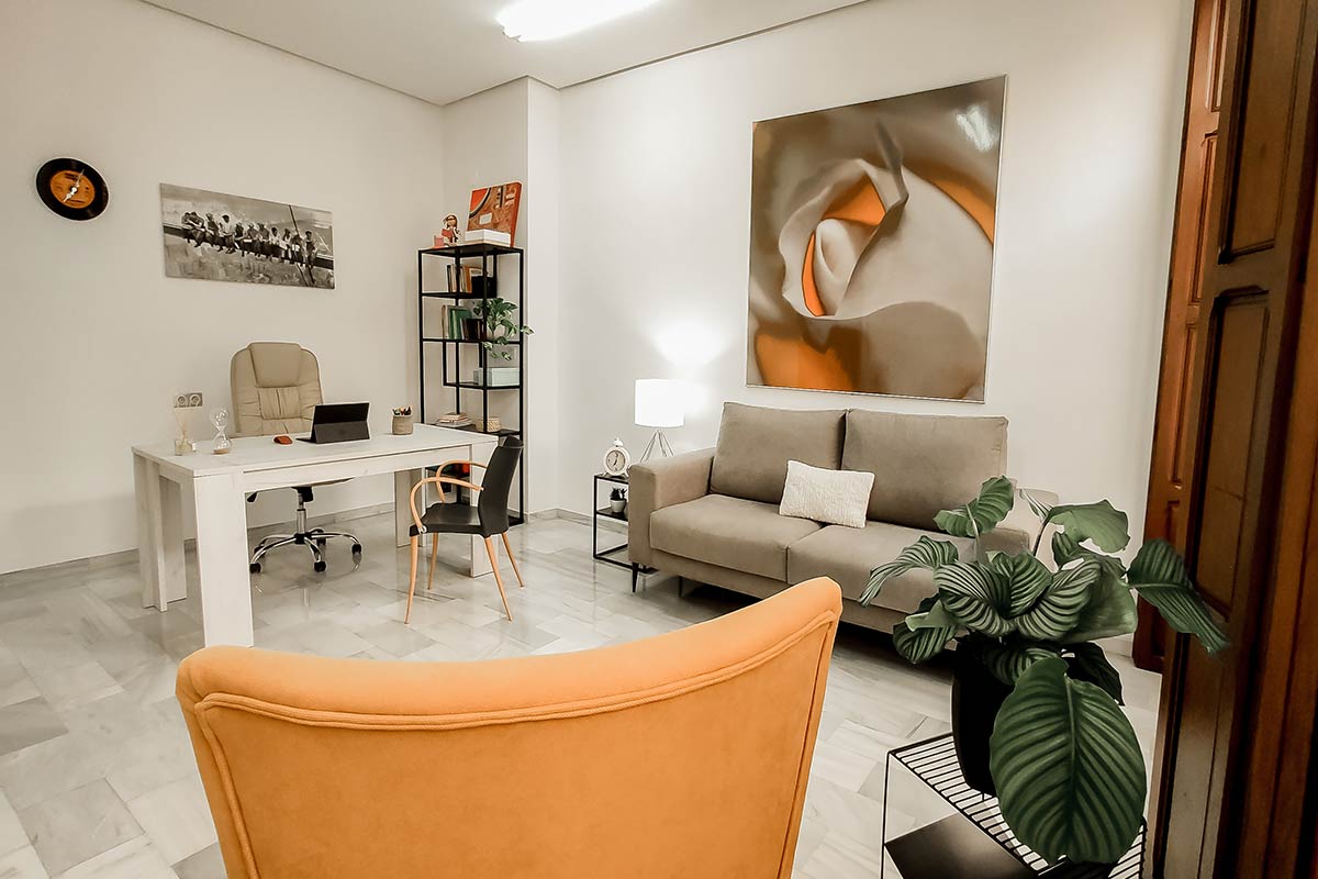 Despacho con la mesa de trabajo, un sofá y un cuadro grande en la pared